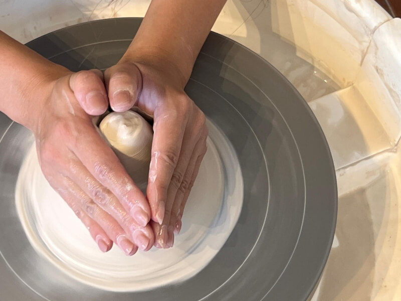 Hands shaping clay on the wheel