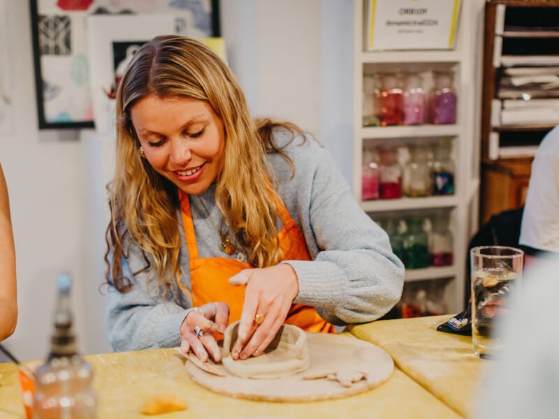 woman hand building with clay at a pottery class