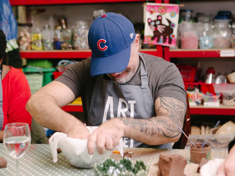 Man in hat and apron working on a craft project in a workshop