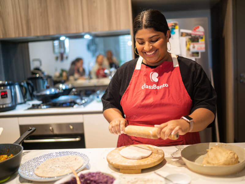 woman smiling and rolling out dough