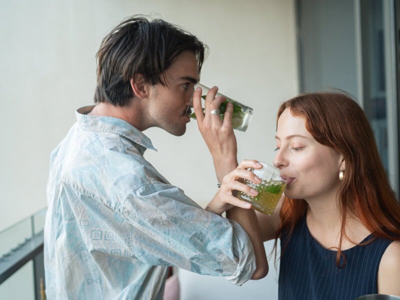 Couple drinking cocktails while arms are entwined
