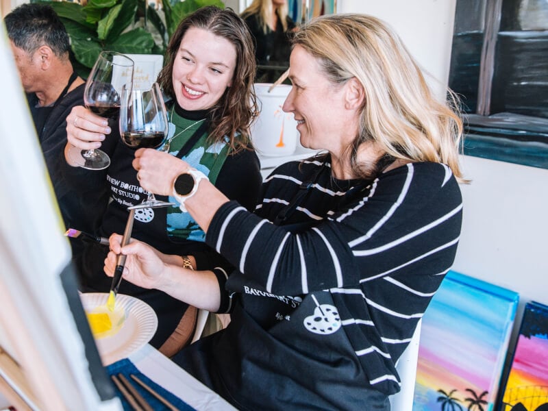 Mother and daughter clinking wine glasses at paint and sip class