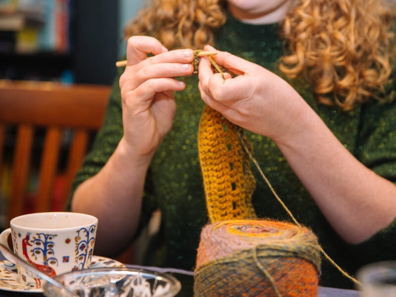 A woman knits a scarf at her textiles gift experience