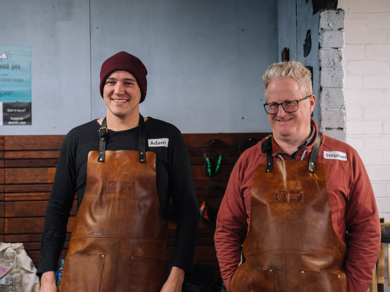 Father and son standing at a blacksmithing class