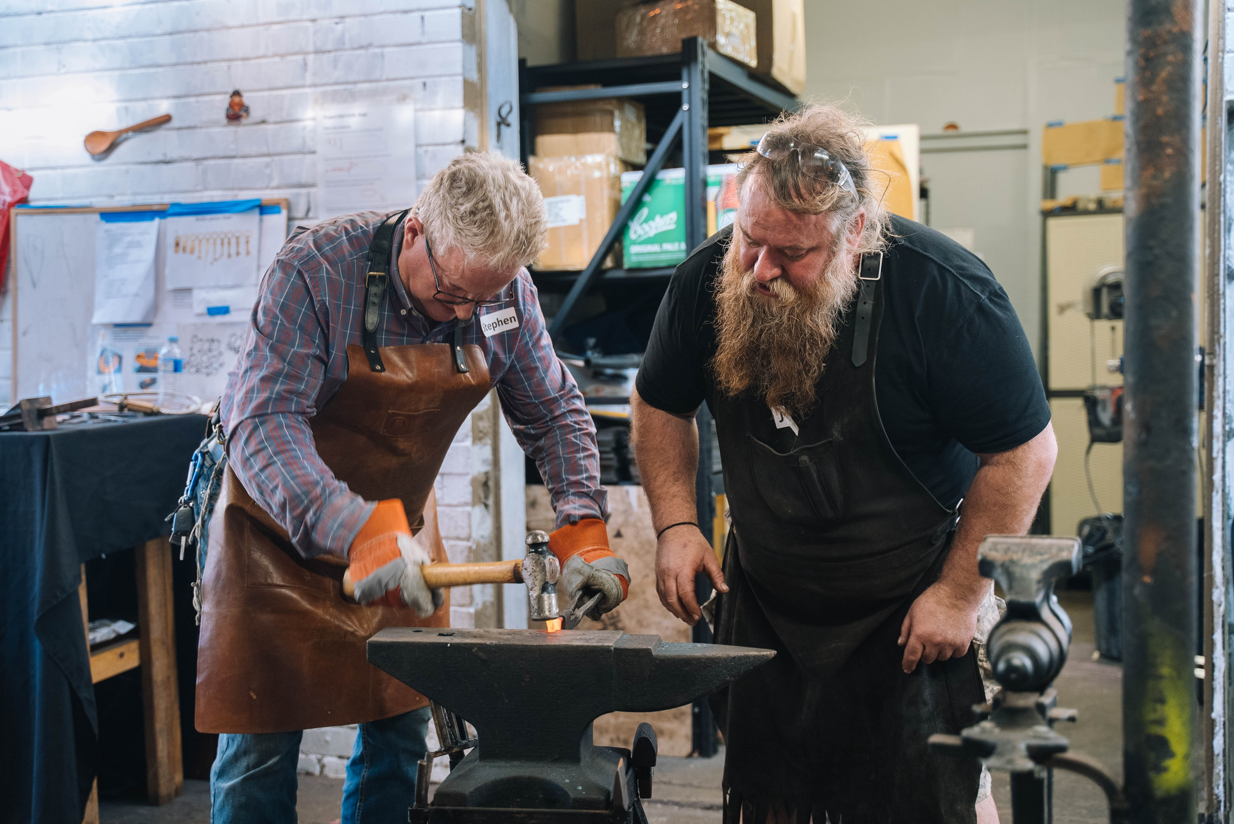 Teacher helping student in a blacksmithing class