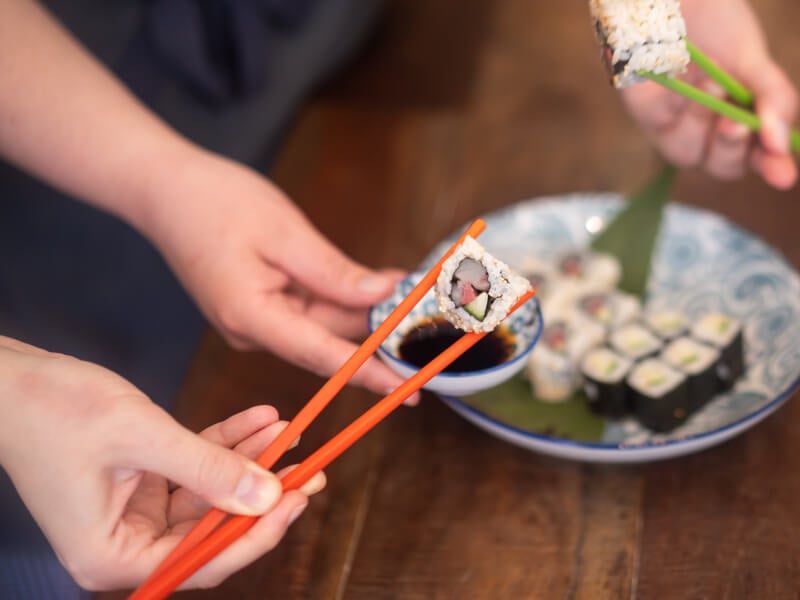 Close-up of person holding sushi with chopsticks