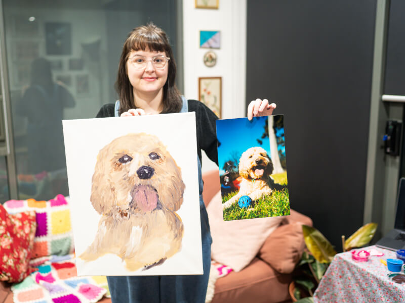 Person showing pet painting and reference photo side by side