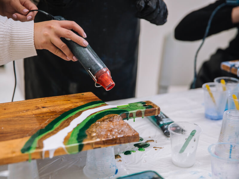 Person blowing resin paints over a wooden board.jpg