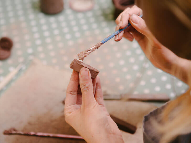 Person painting a piece of terracotta