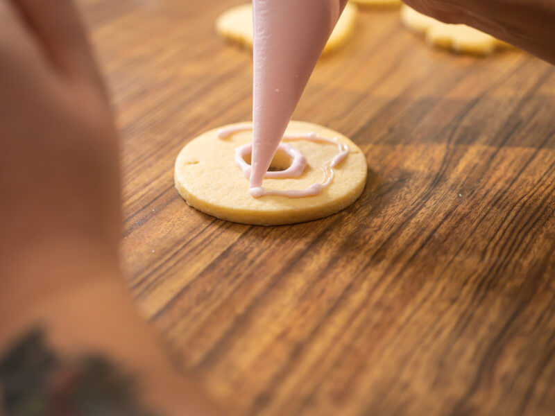 Piping icing onto a donut-shaped cookie