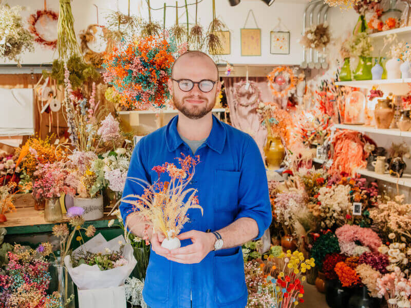 Man showing his DIY dried flower arrangement in a floral shop