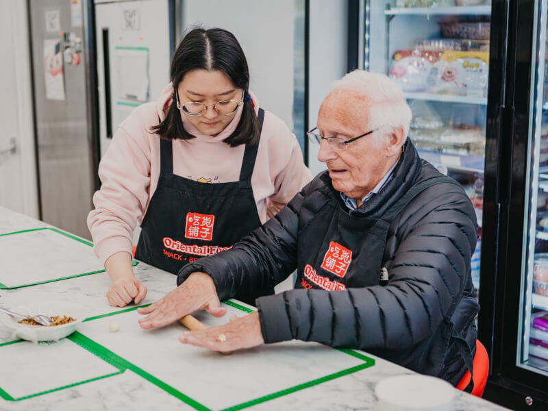 Teacher helping student at a dumpling making class