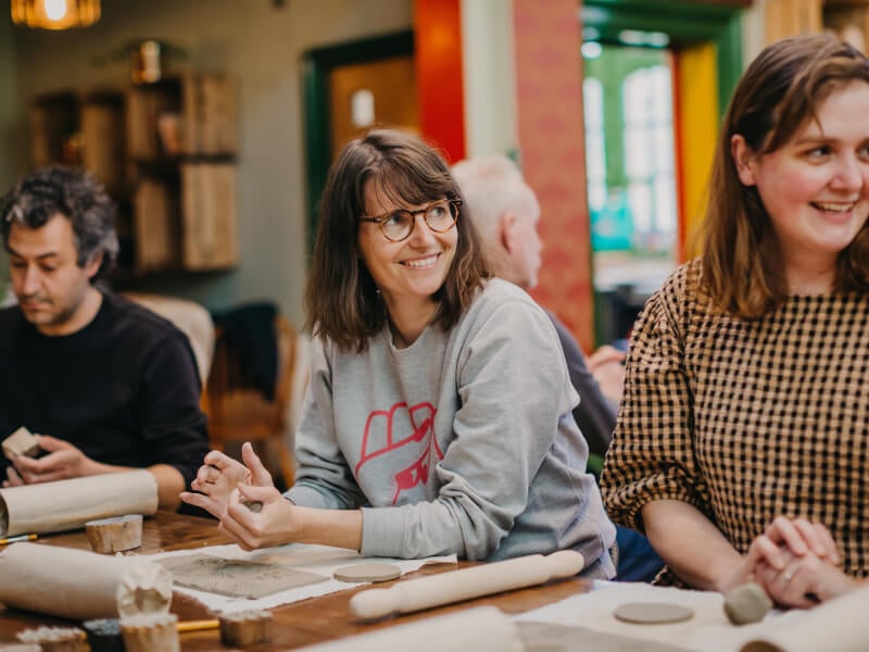 Smiling woman in focus at a pottery class