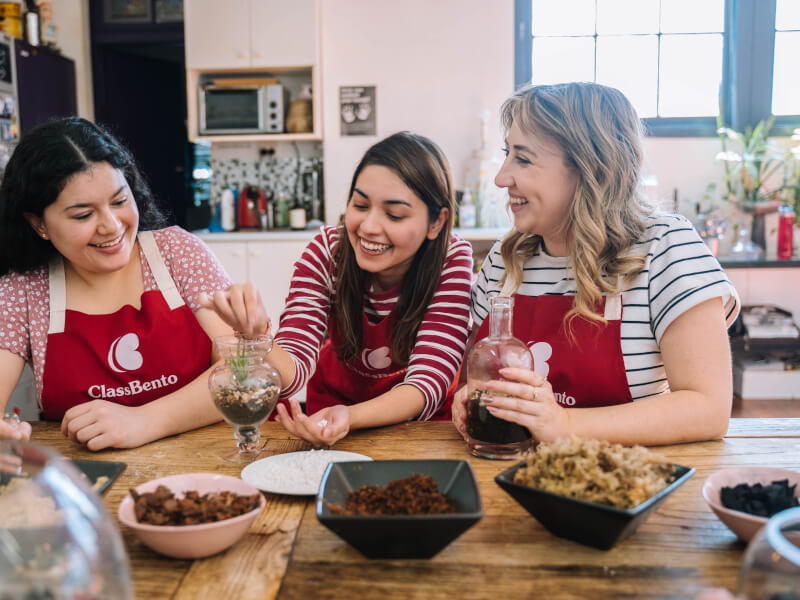 Smiling women in ClassBento aprons making terrariums
