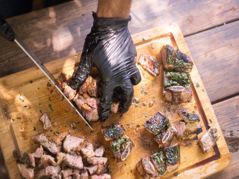 Close-up of person cutting BBQ steak