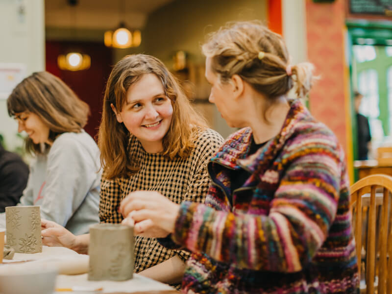 Coworkers socialising and making pottery at a clay hand building class