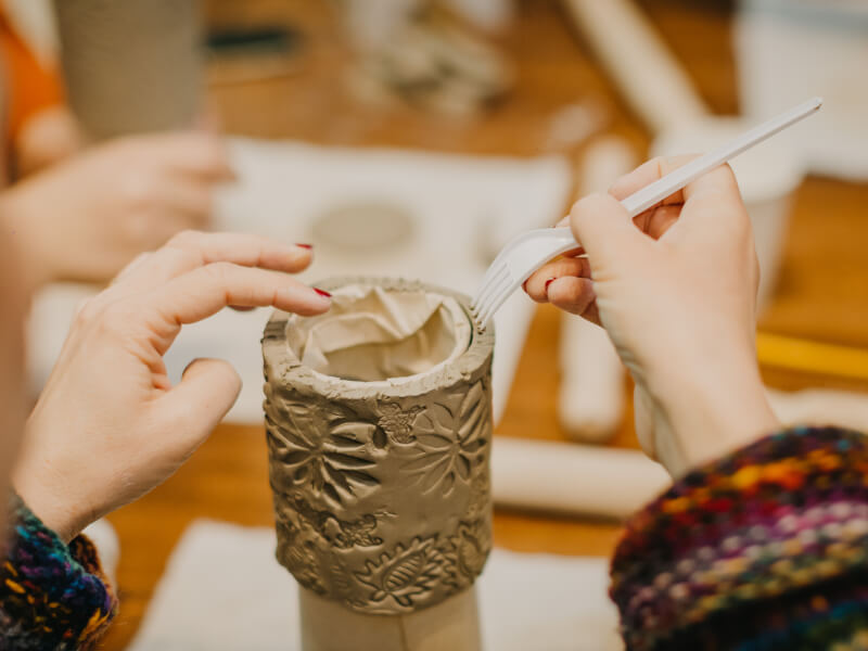 Close-up of woman adding texture to pottery