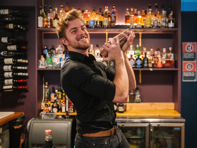 mixologist smiling and shaking cocktail