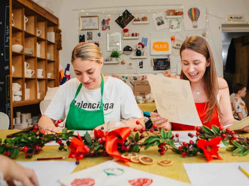 Two smiling women doing Christmas crafts