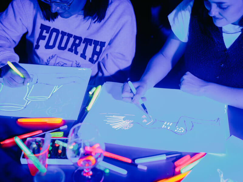 Two people making art at a UV drawing class that was gifted