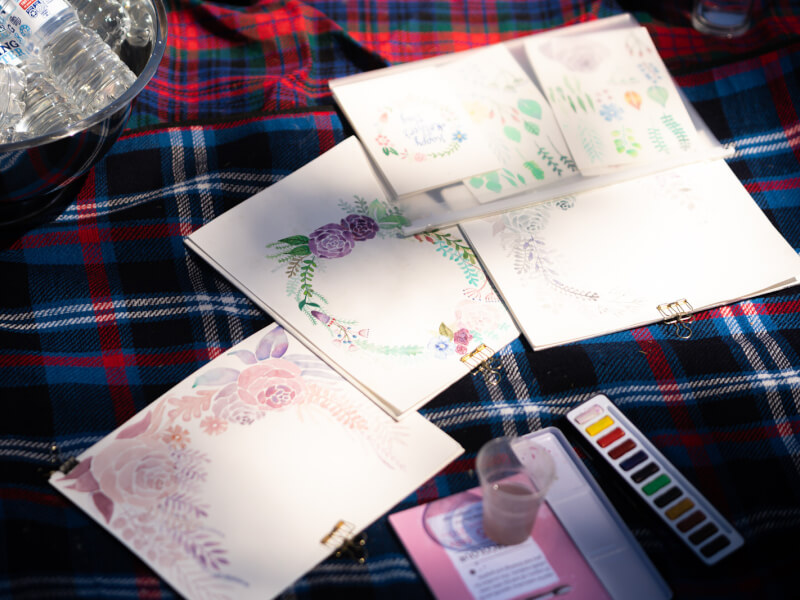 DIY watercolour artworks laid out on a picnic