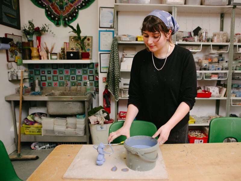 Woman dipping an object into a bucket of purple paint