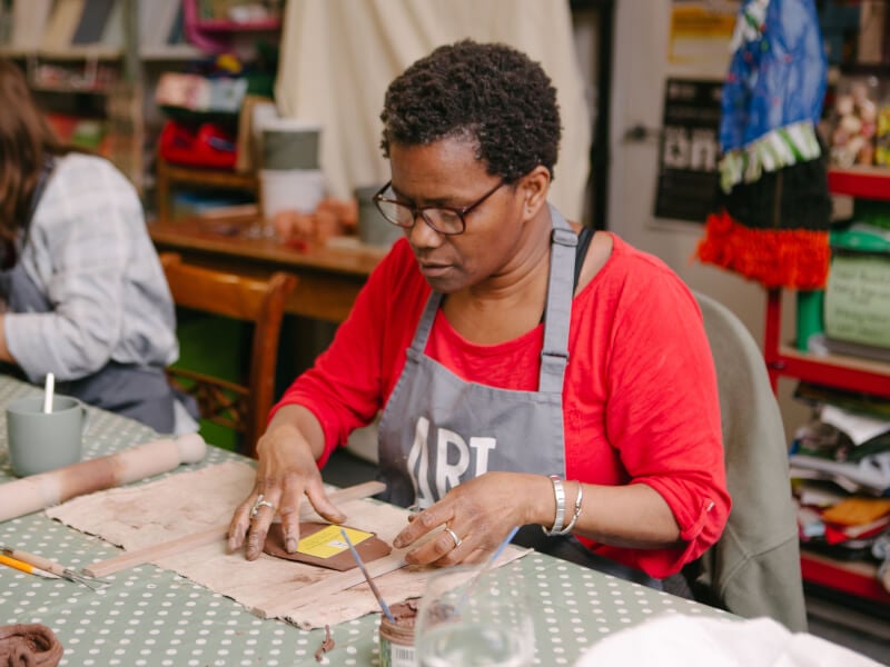 Woman looking intently at her clay in a pottery workshop