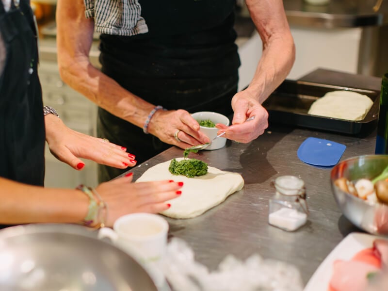 Woman spooning herbs into pastry dough 