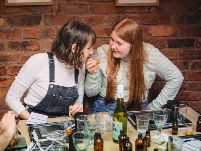 Women smelling essential oils in beakers