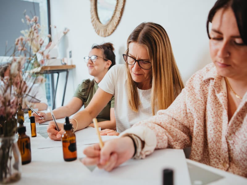 Women writing something down in a perfume-making workshop