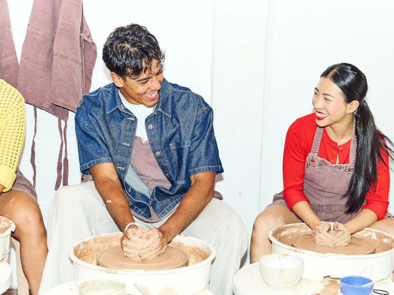 People smiling at each other in a wheel throwing class