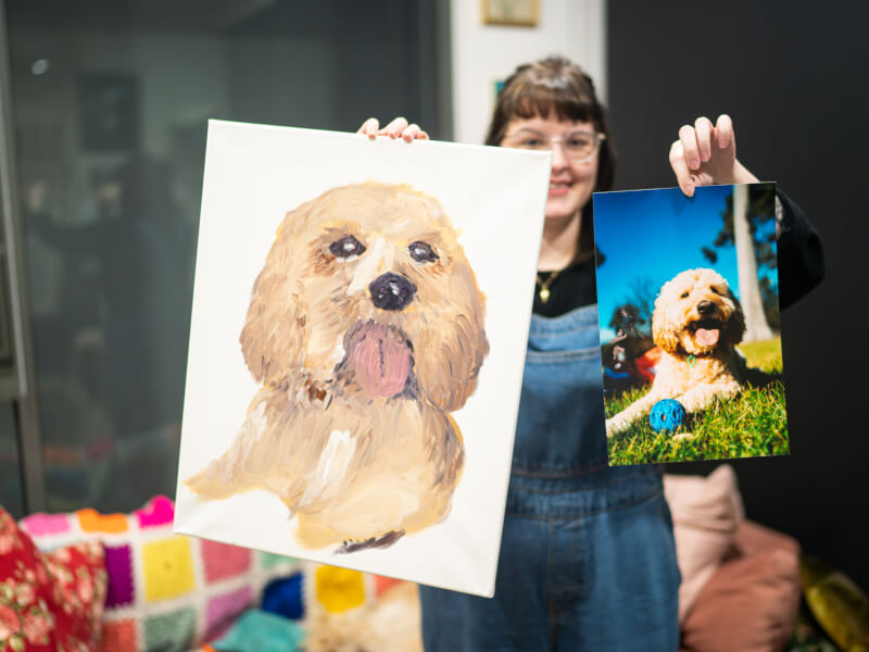A woman poses with a painting of her pet