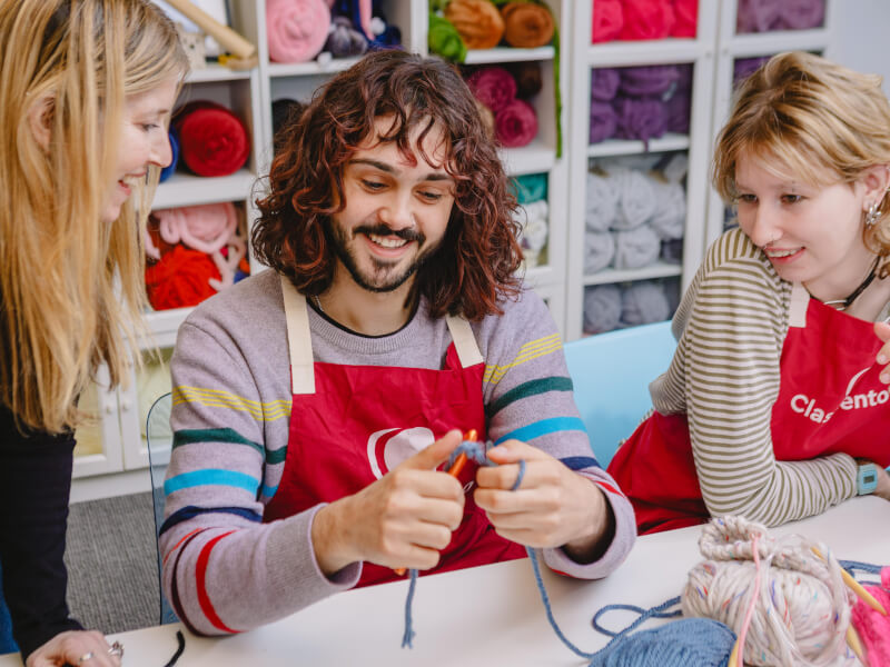 A man learns to knit under the guidance of a teacher
