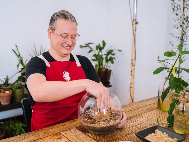 A happy man building a terrarium in a workshop