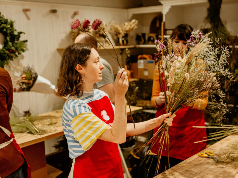 A woman adding flowers to her bunch at a flowers and plants class