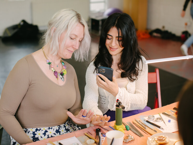 Two women admiring their handmade jewellery at a Brisbane workshop