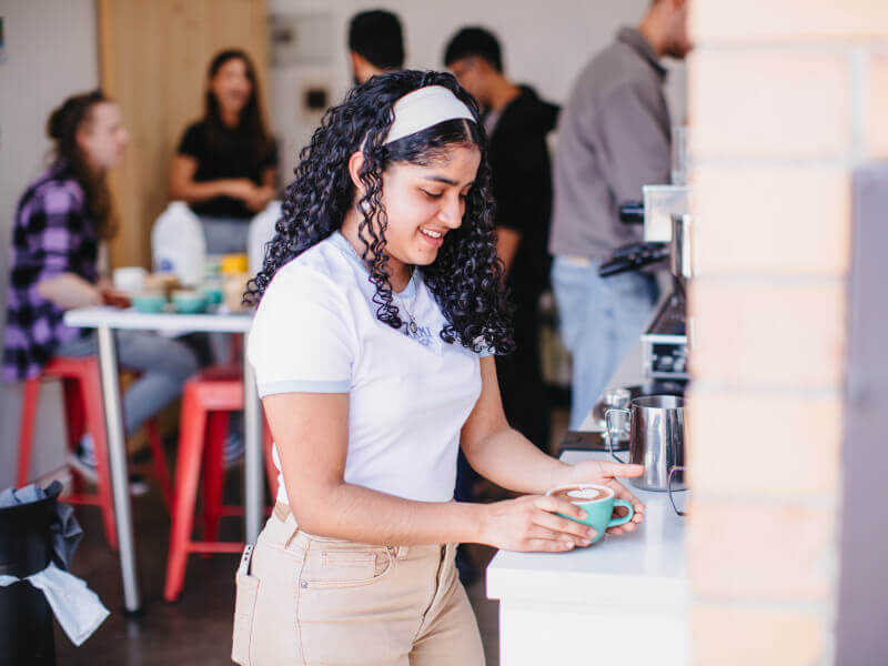 A woman admires her cup of coffee at a barista course