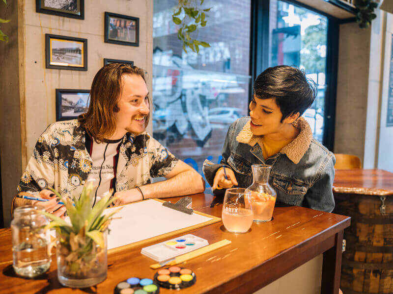 A man and his girlfriend smiling at a paint and sip class