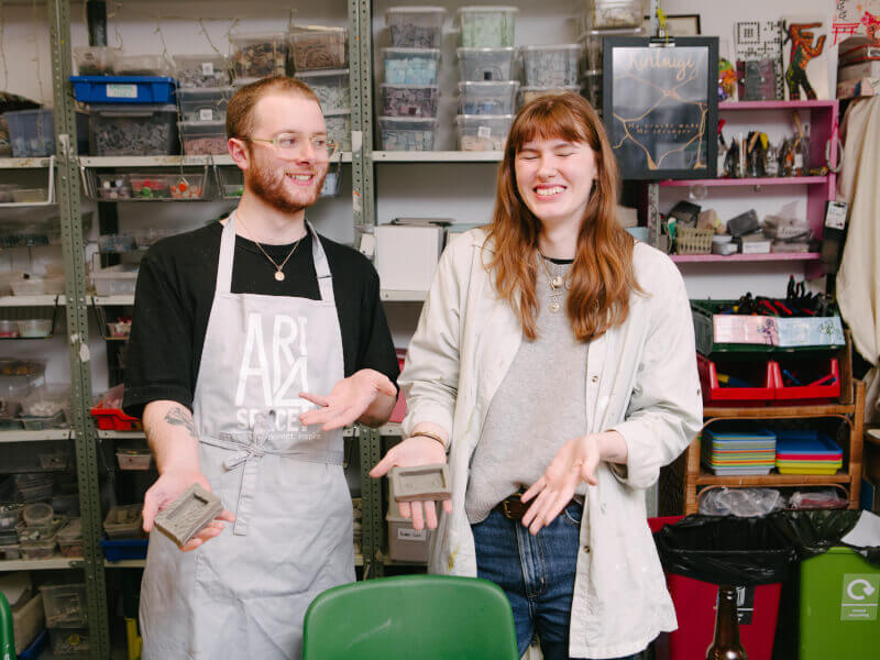 A boyfriend and girlfriend show off what they made at a pottery class