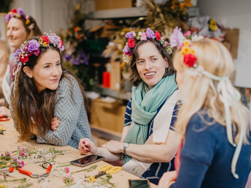 Three women wearing flower crowns at floristry class