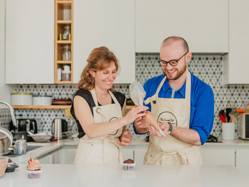 Mother and son decorating cupcake with piping
