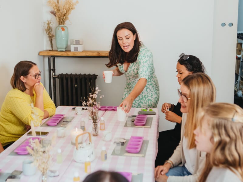 Women at candle making class sitting around a table with purple candle moulds