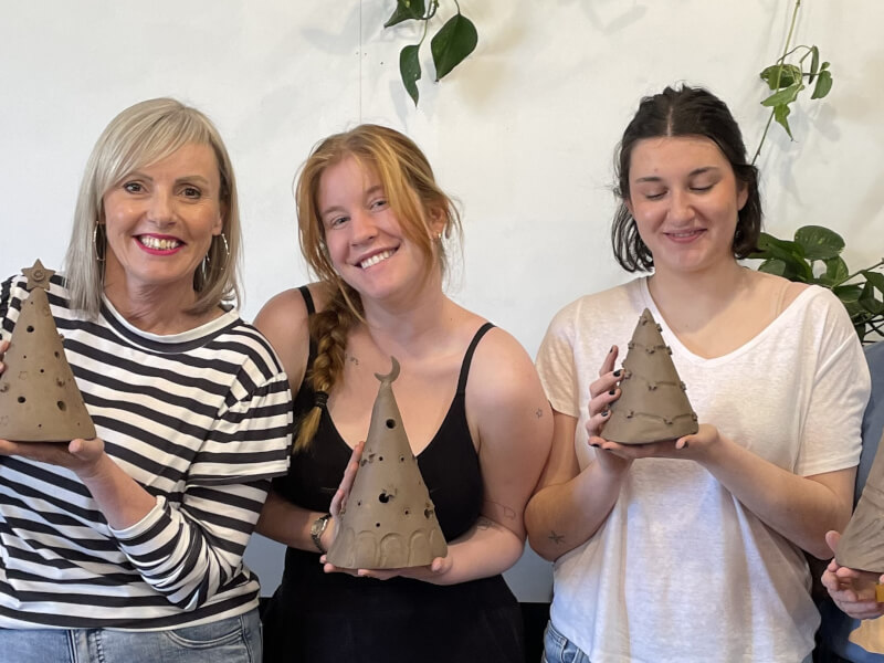 A group of friends pose with their ceramic Xmas trees