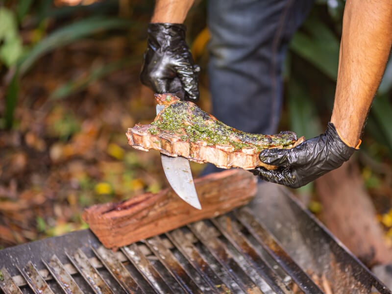 Juicy slab of meat covered in chimichurri being showed off at bbq cooking class