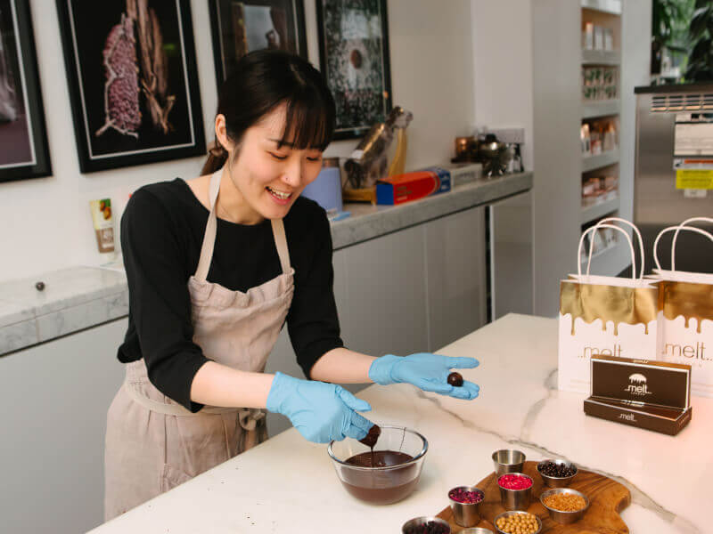 A woman laughing and getting messy with chocolate at a chocolate class she was gifted for her anniversary