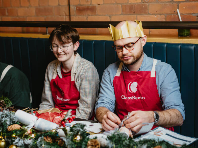 Two people making Christmas crackers during a Christmas workshop