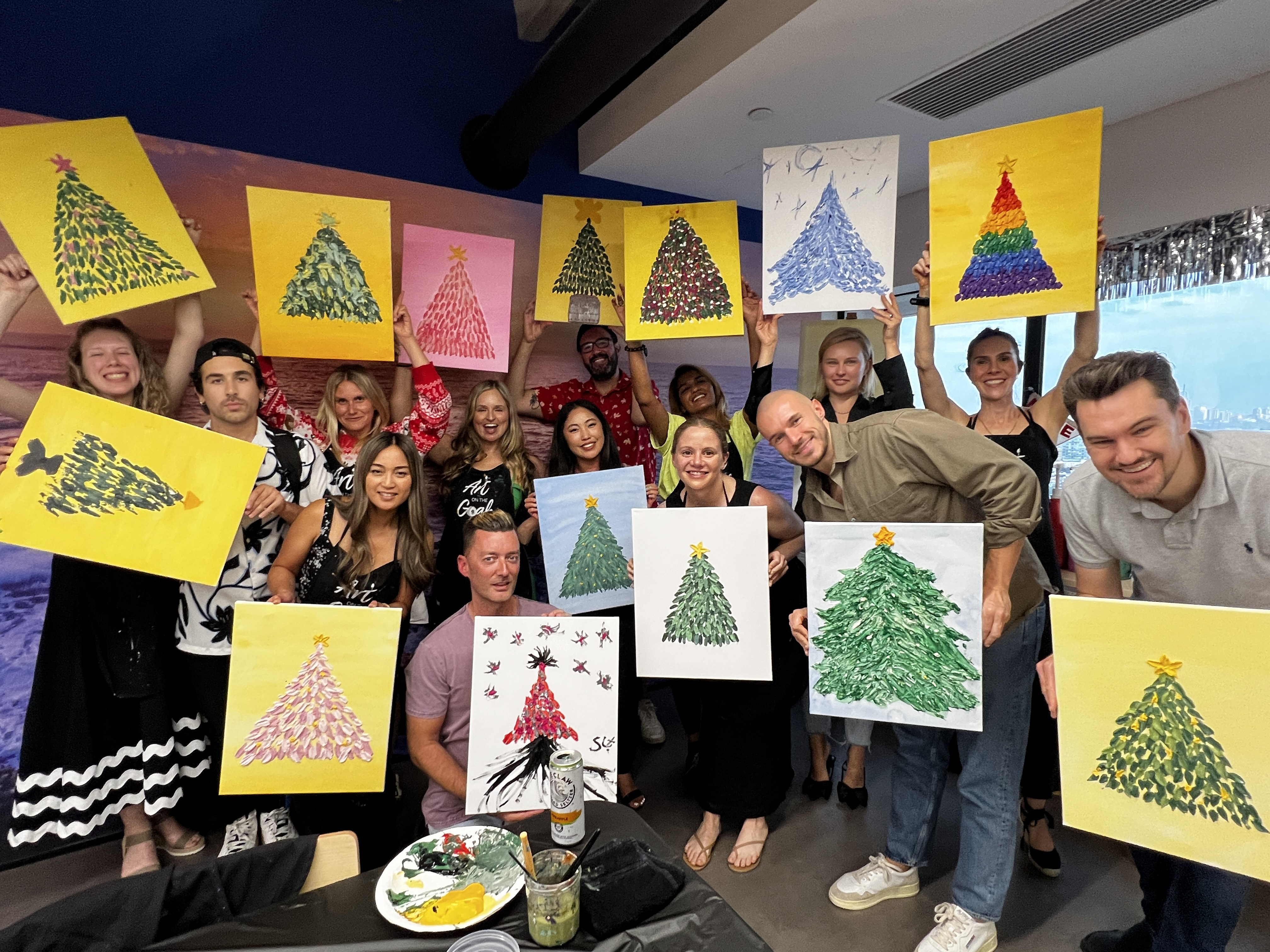 Team showing off finished Christmas tree paintings