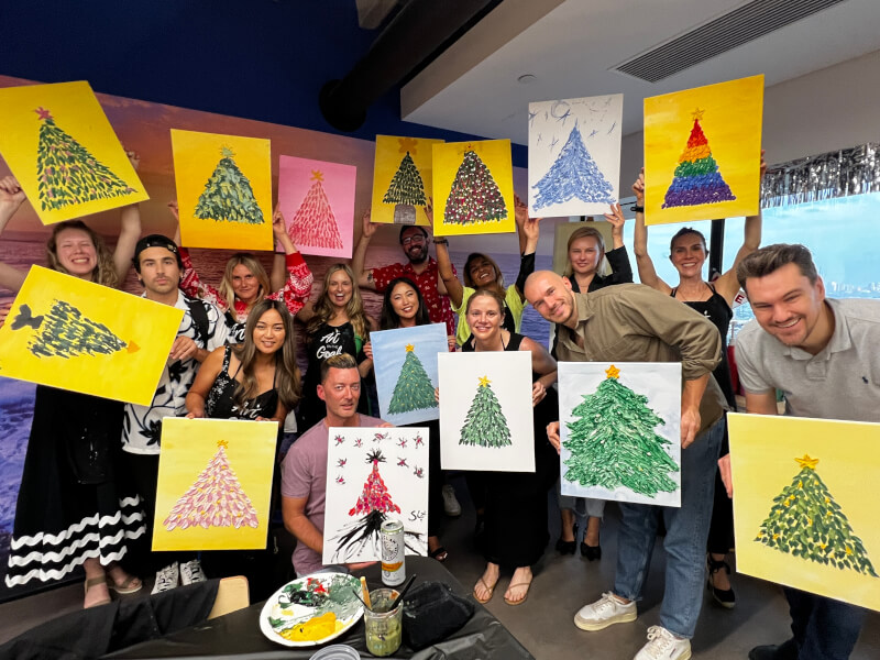 Colleagues holding their Christmas tree paintings