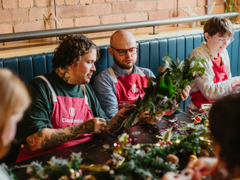 Group of friends smiling while making wreaths
