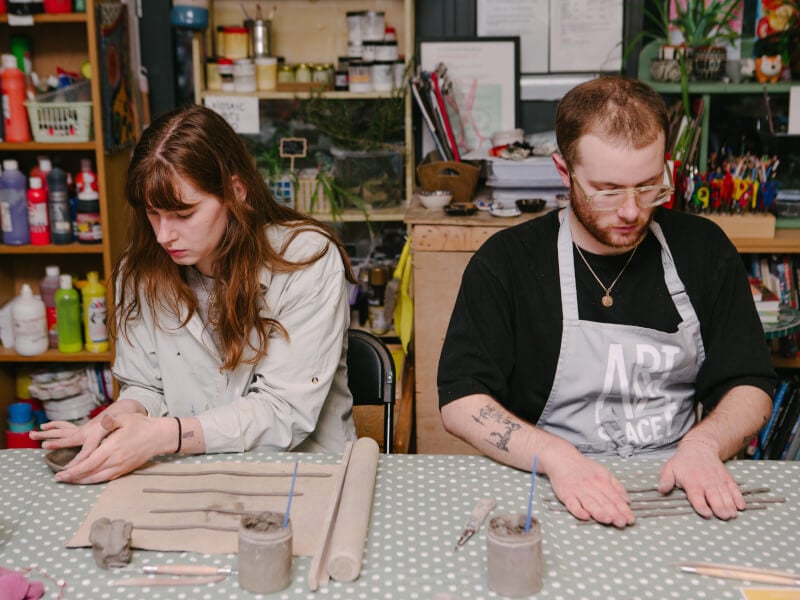 A couple hand building with clay